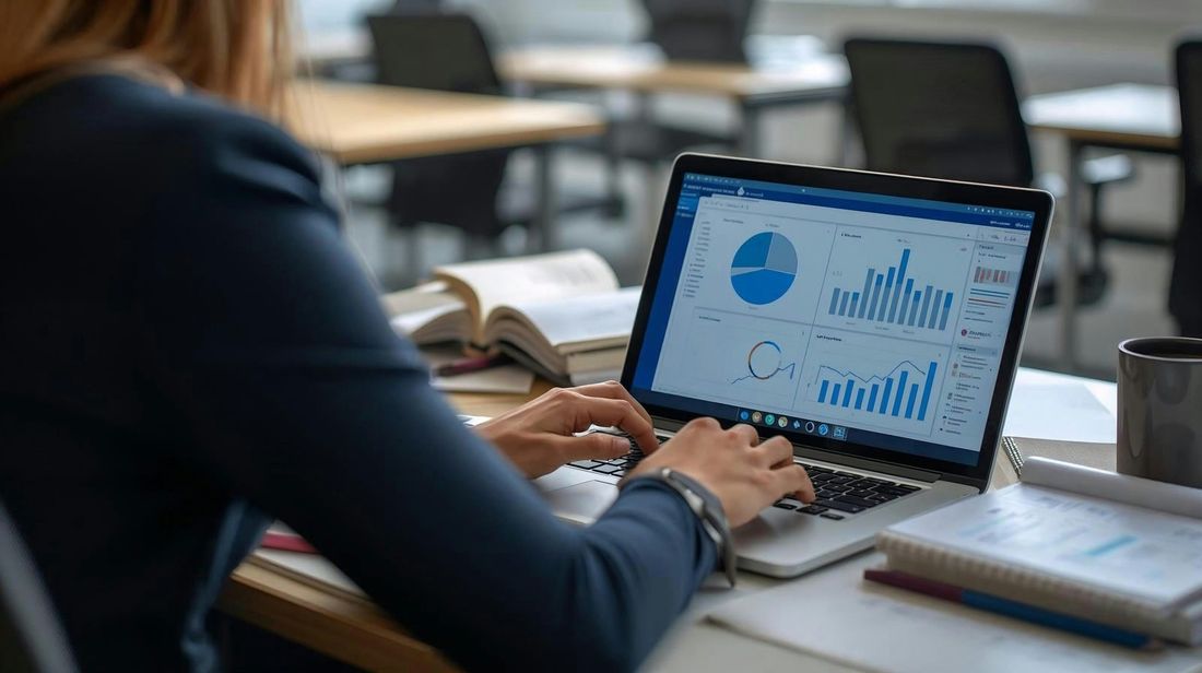 Person working at a laptop showing security-style charts and graphs on a desk in an office