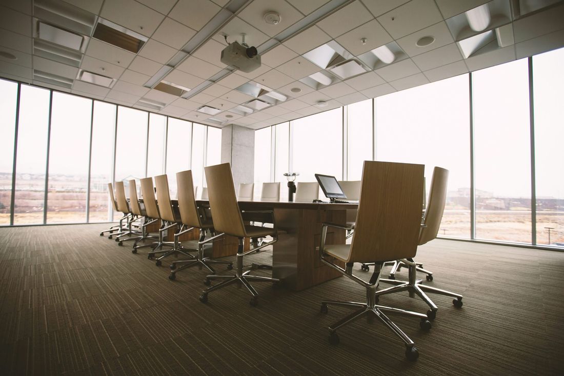 Empty boardroom with a long table, chairs and floor-to-ceiling windows