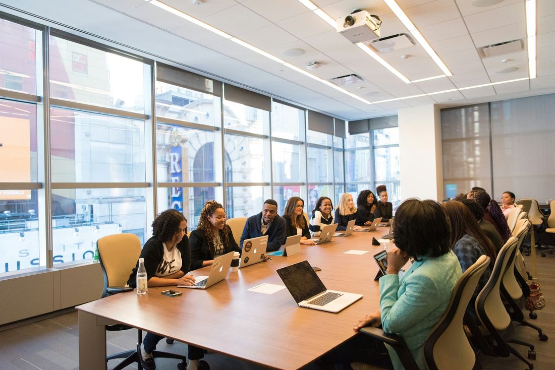 Staff seated around a long table with laptops during a training session in a bright meeting room